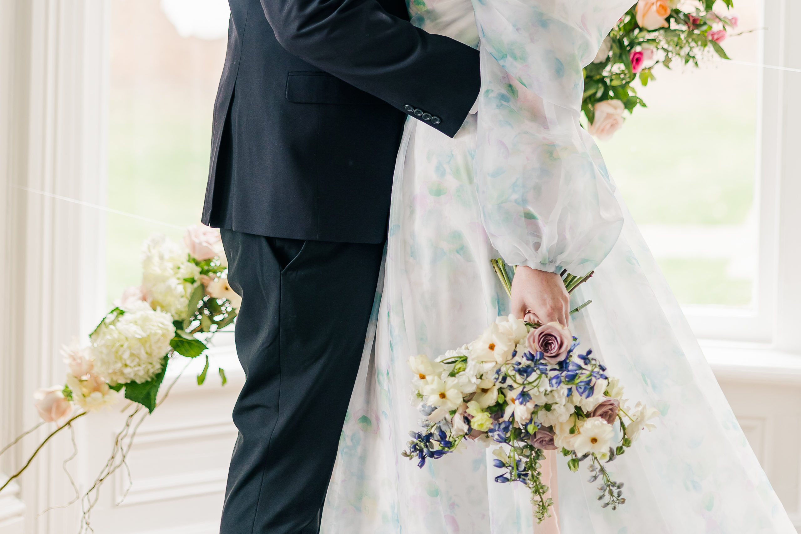 Newly married couple closeup of groom holding bride at waist with bouquet